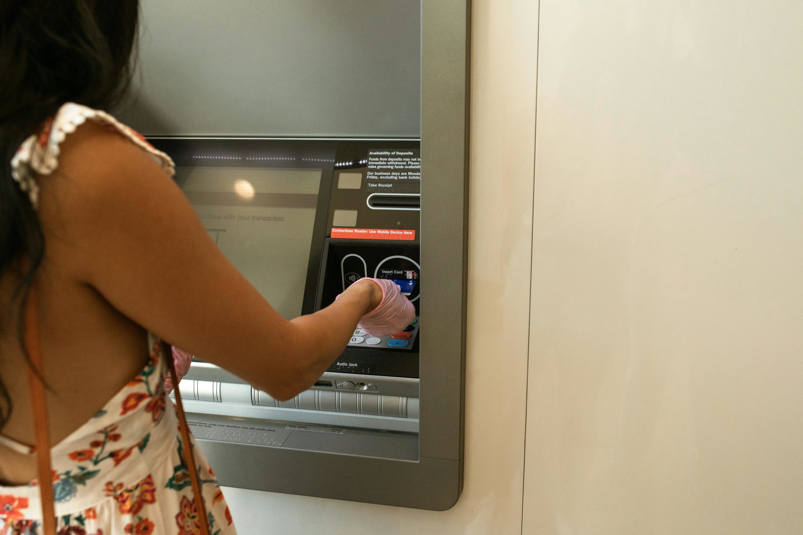 Frau Im Roten Weißen Und Grünen Blumenkleid, Das Nahe Atm Maschine Steht