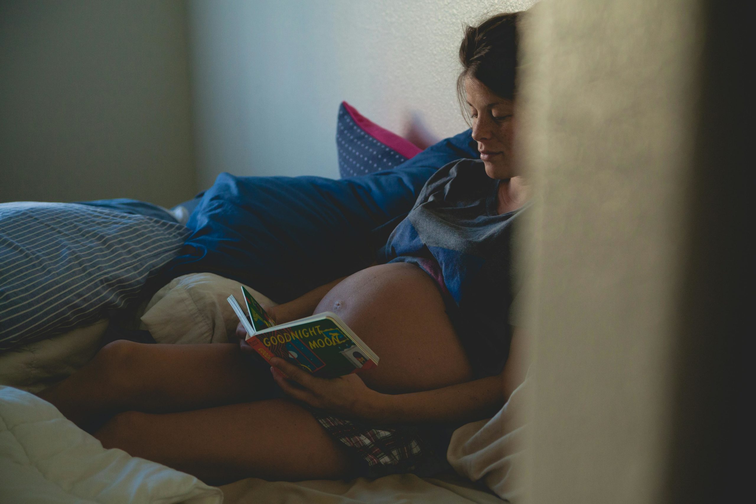 Schwangere Frau Sitzt Auf Bett Und Liest Buch