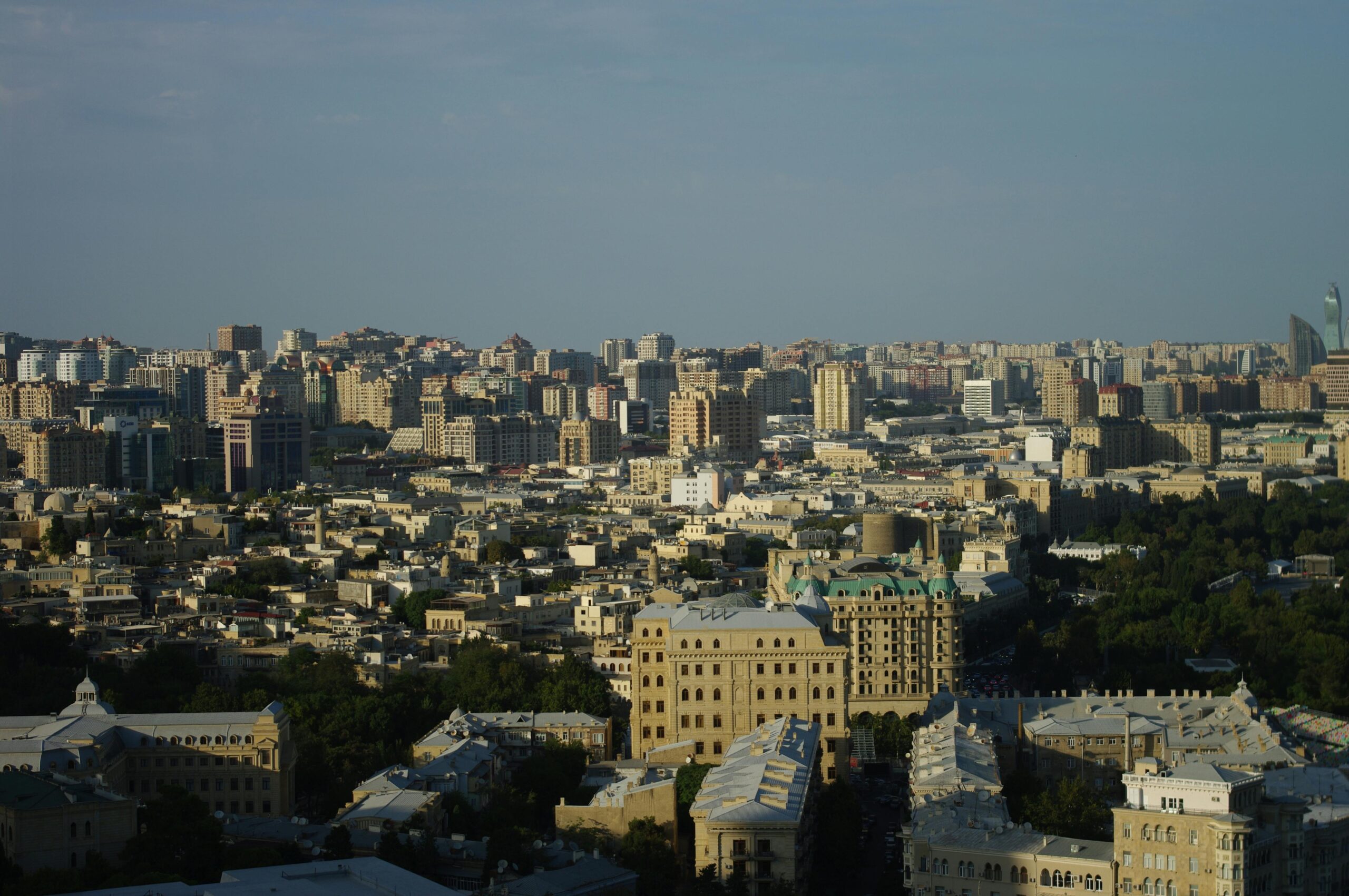 Luftaufnahme der Skyline von Baku mit moderner Architektur und urbaner Dichte unter einem klaren blauen Himmel.