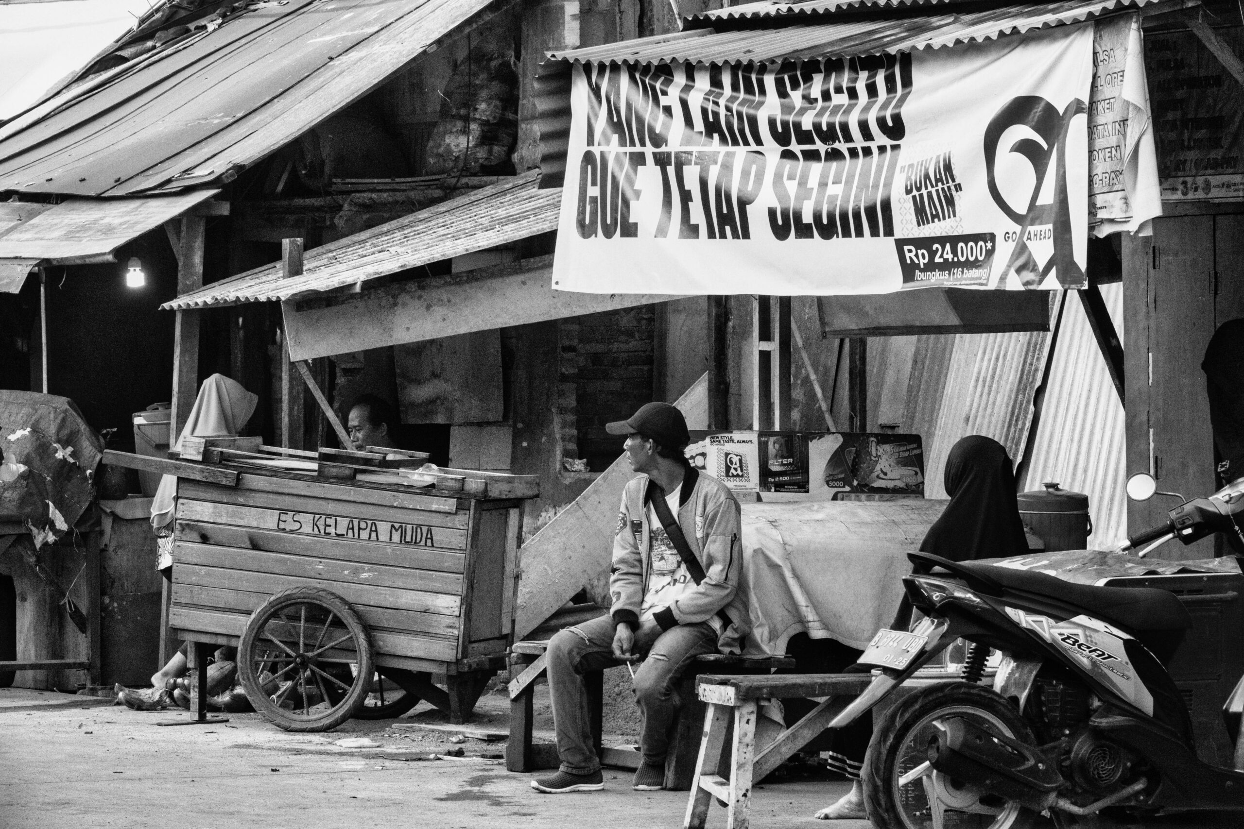 Schwarz-weiße Straßenszene in Jakarta, die das lokale Leben mit Essensständen und Menschen zeigt.