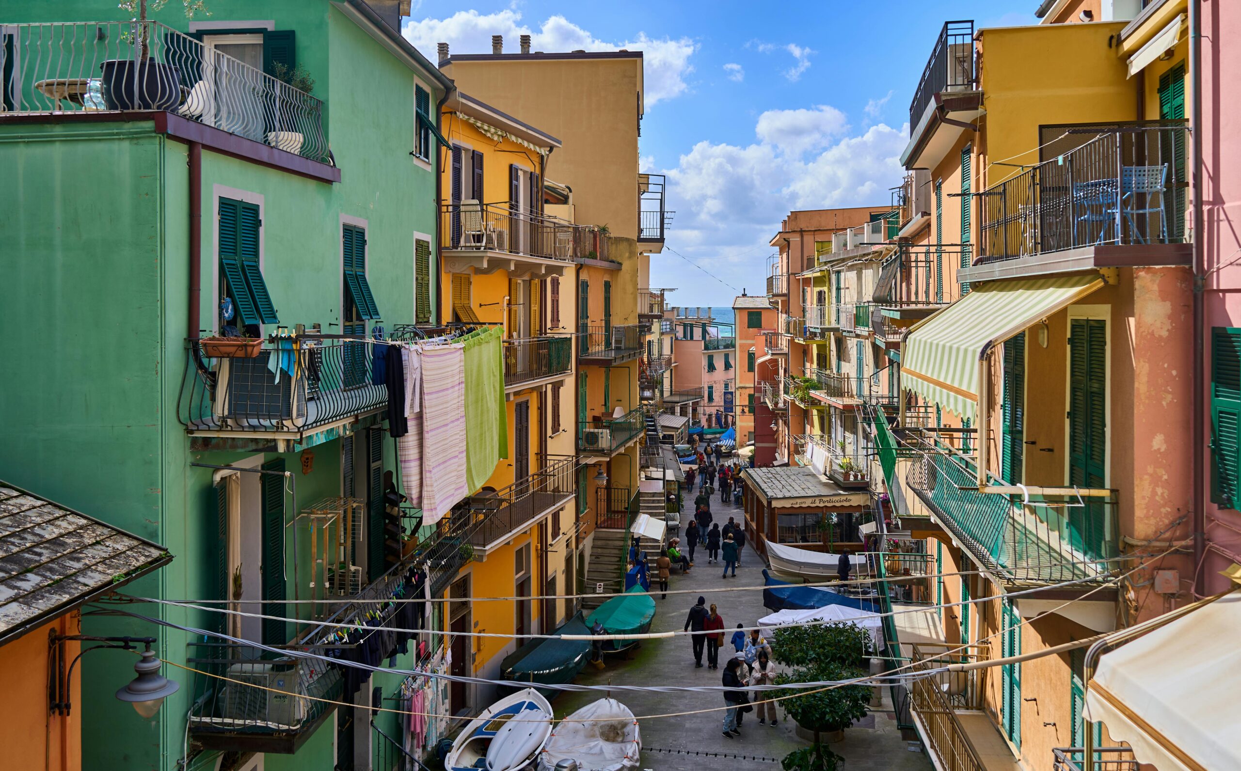 Eine belebte Straße im italienischen Riomaggiore mit farbenfrohen Gebäuden und geschäftigem Treiben.