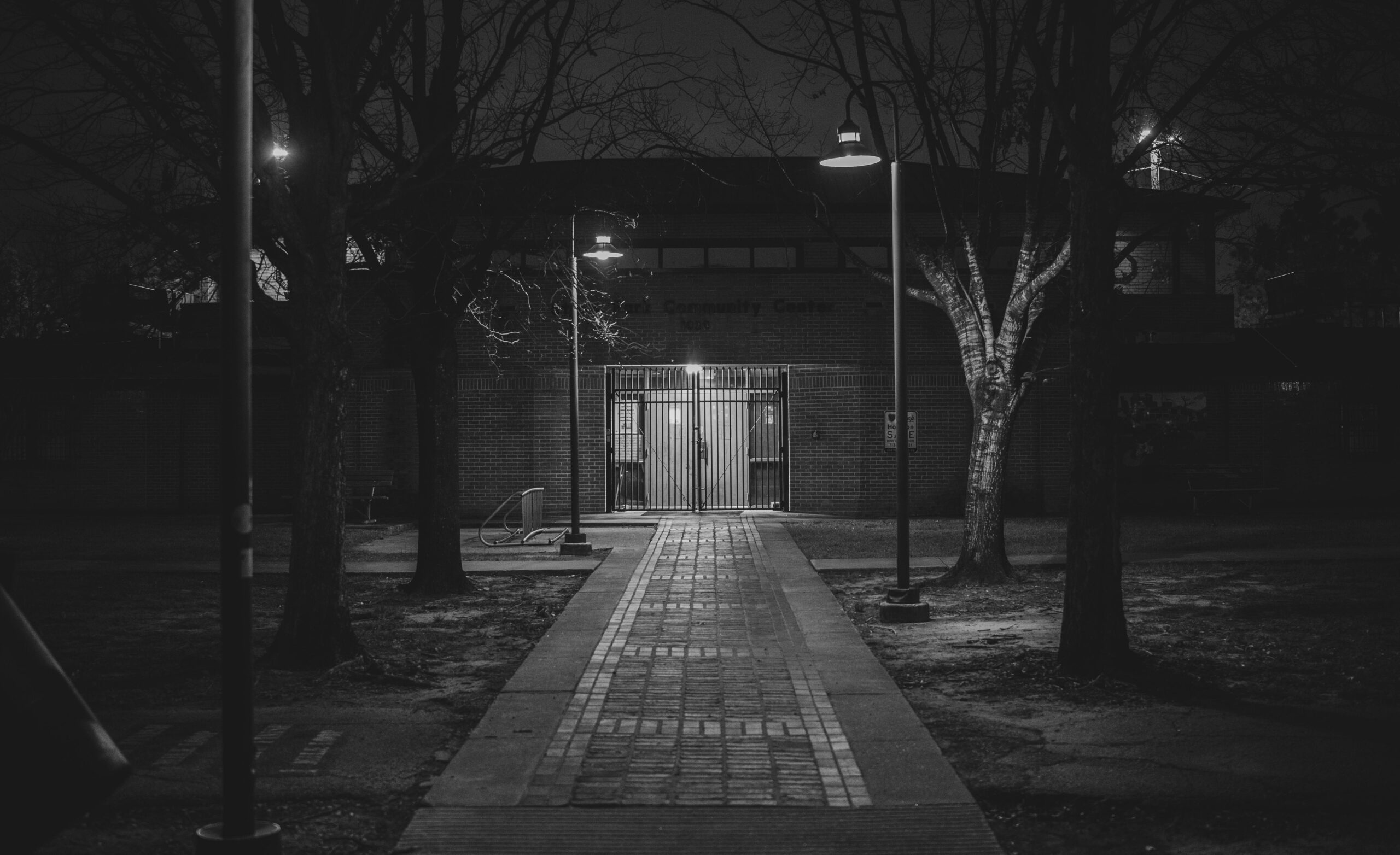Eine dunkle, stimmungsvolle Gasse bei Nacht in Houston, Texas. Monochrome Straßenlaternen verstärken die Szenerie.