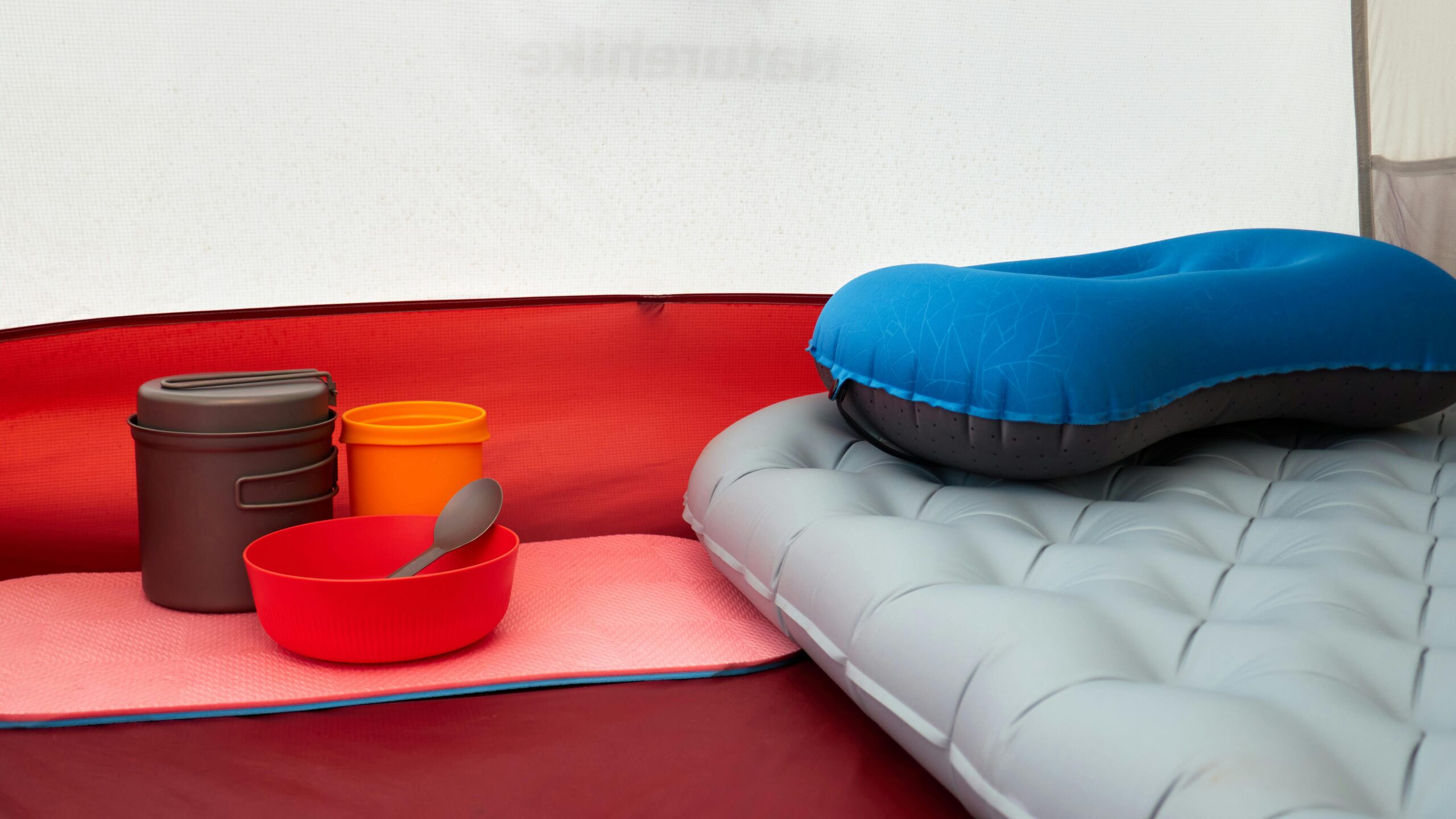 Innen ein Zelt mit aufblasbarem Kissen, Kochgeschirr und Isomatte, ideal zum Campen.