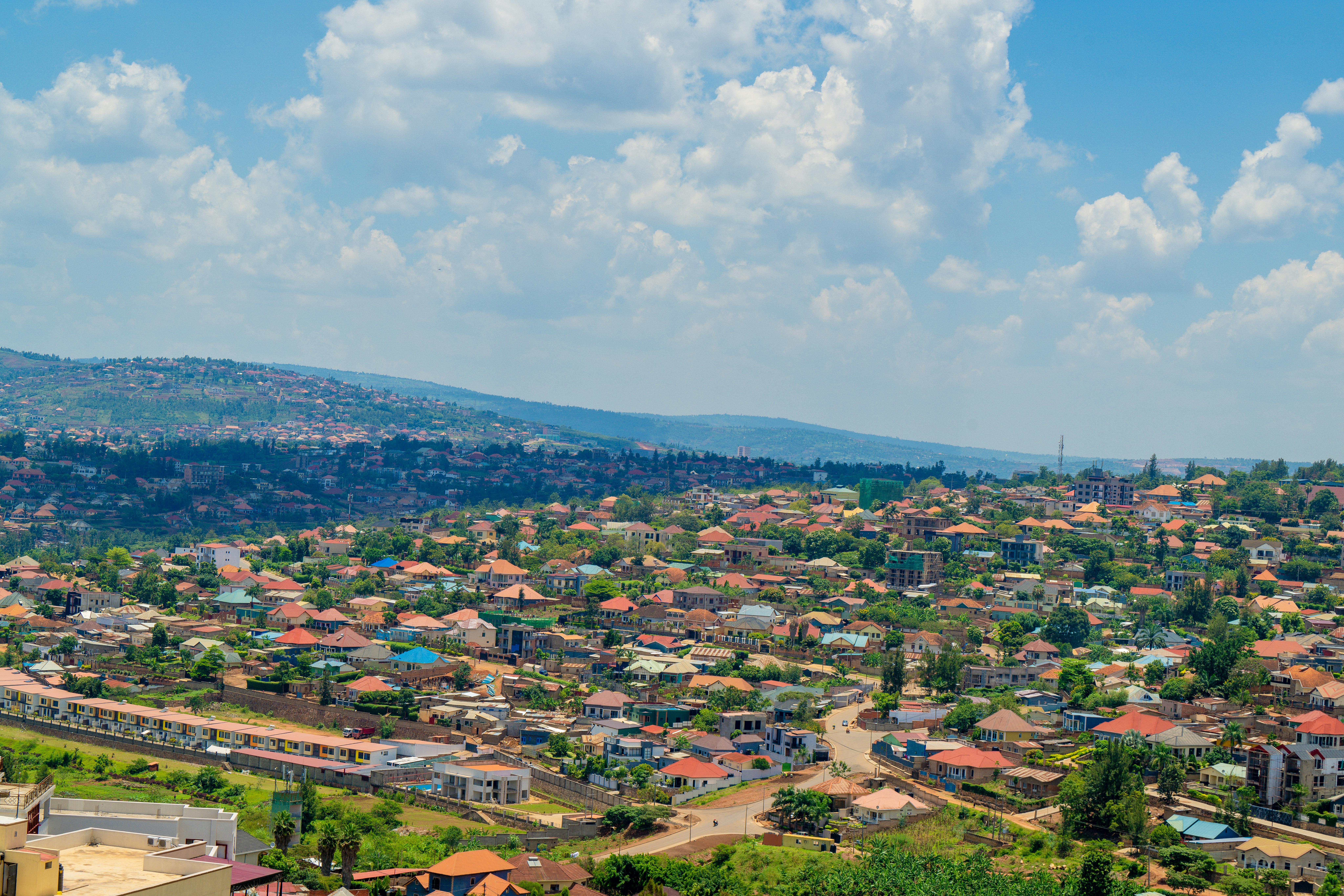 Luftaufnahme der Stadtlandschaft von Kigali mit farbenfrohen Dächern und lebendigem Grün unter einem strahlenden Himmel.
