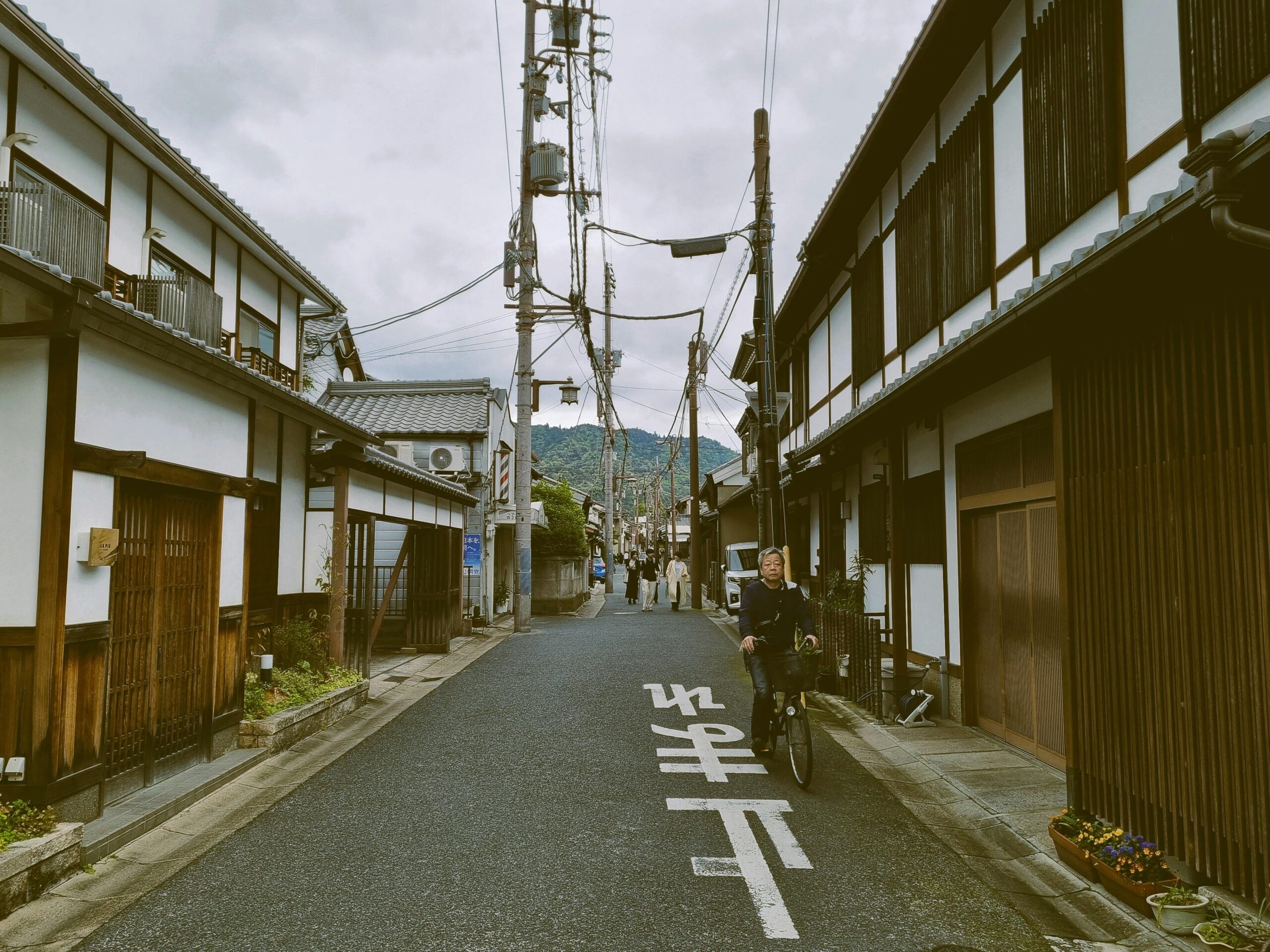 Bezaubernde Szene eines Radfahrers auf einer traditionellen japanischen Straße, gesäumt von Holzhäusern.