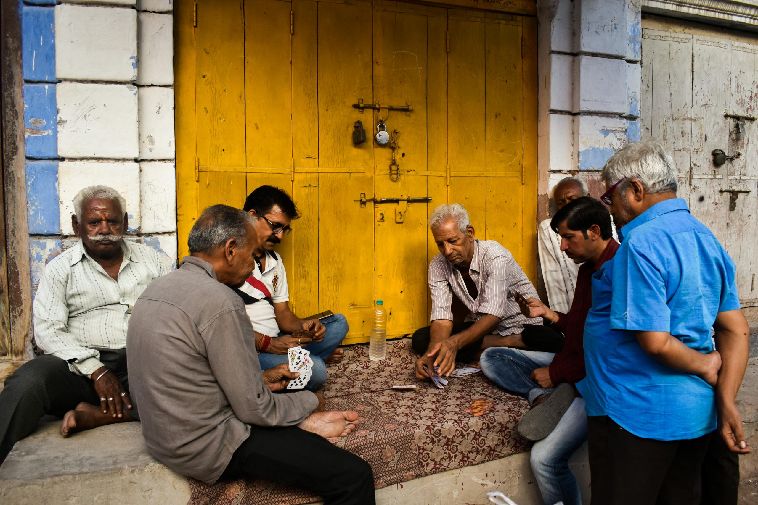 Ältere Männer spielen Karten auf einer Straße in Jodhpur, Rajasthan und zeigen das pulsierende Leben vor Ort.