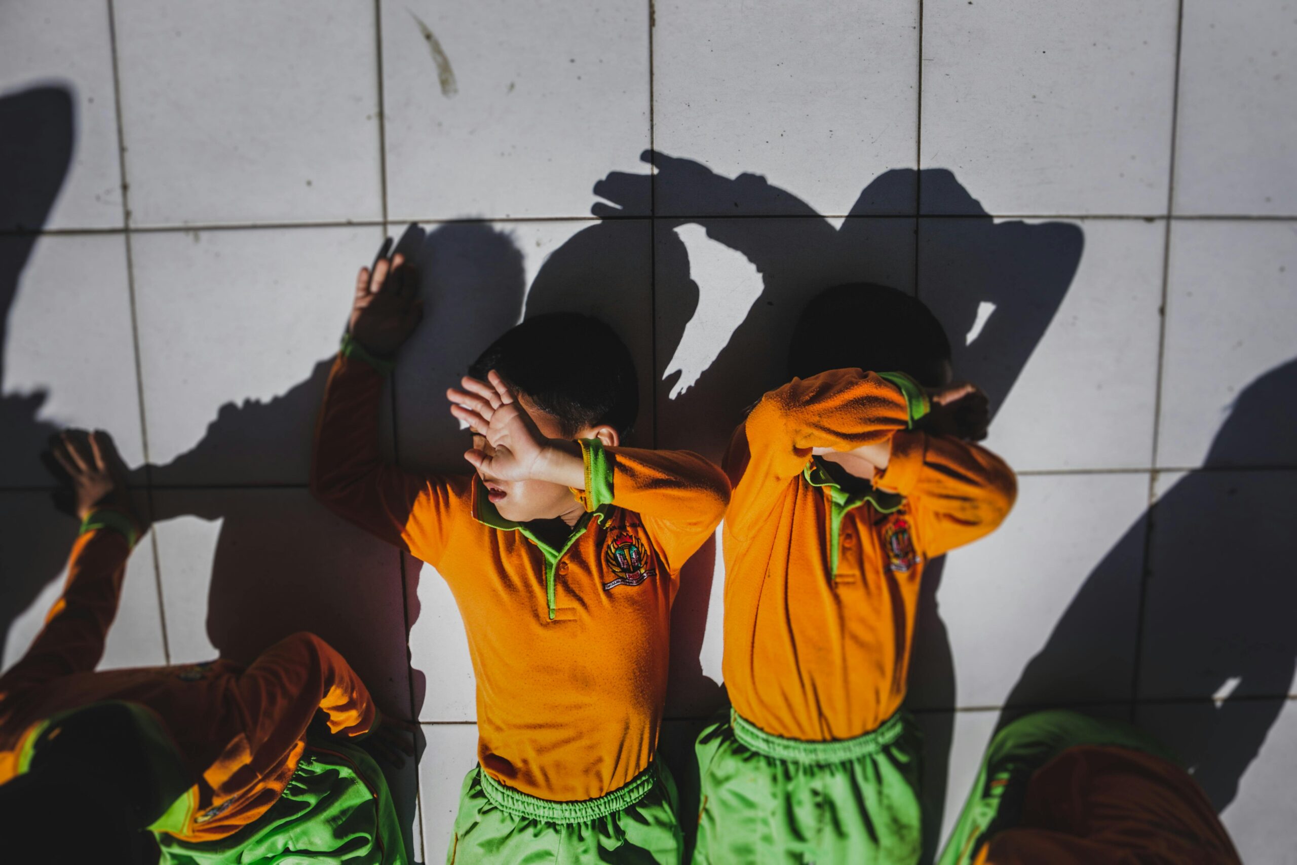 Eine Gruppe von Kindern in Schuluniformen blockiert das Sonnenlicht auf dem Fliesenboden.