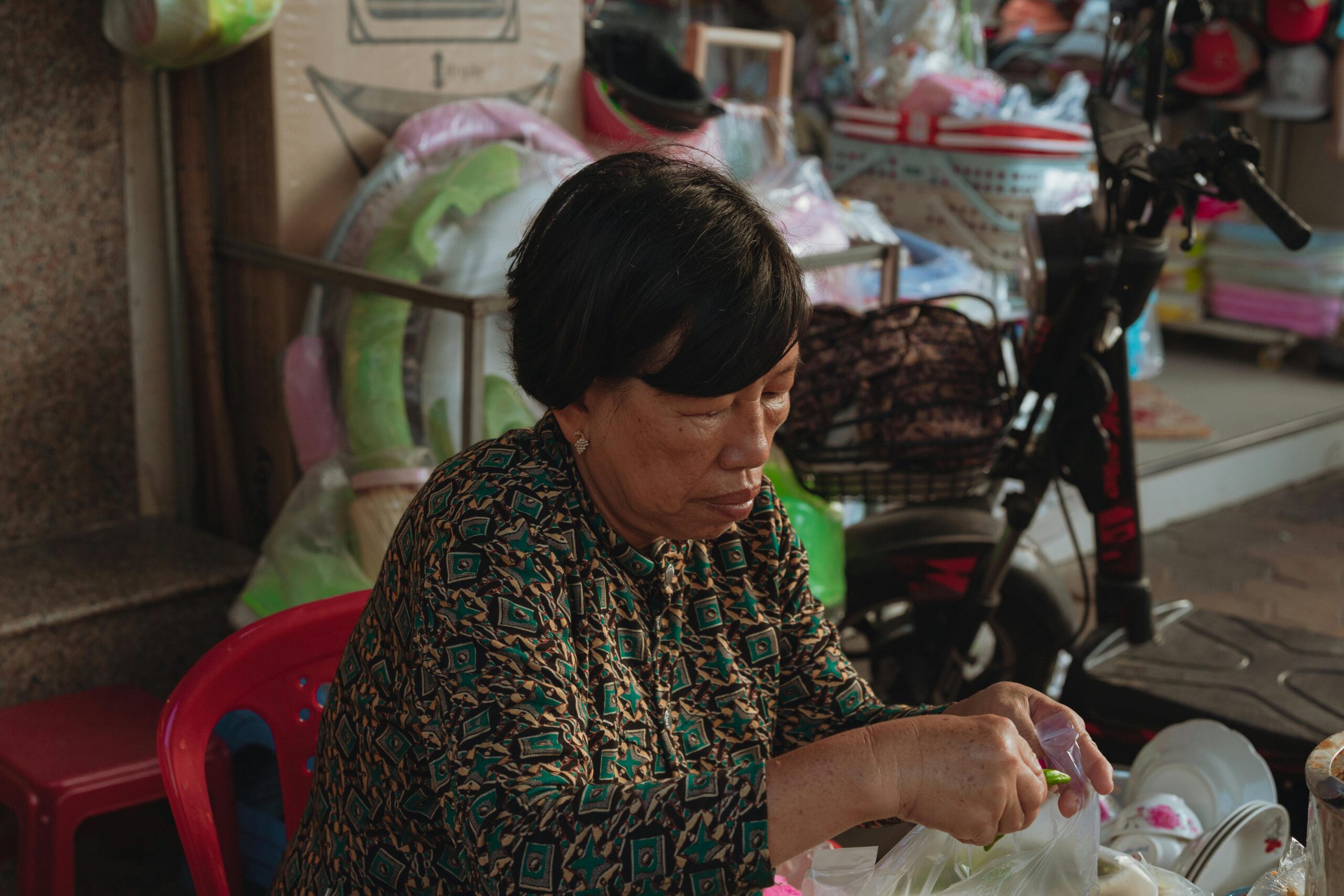 Eine ältere Frau bereitet Waren auf einem Straßenmarkt in Bình Thuáºn, Vietnam, vor. Eingefangen in einem spontanen Moment.